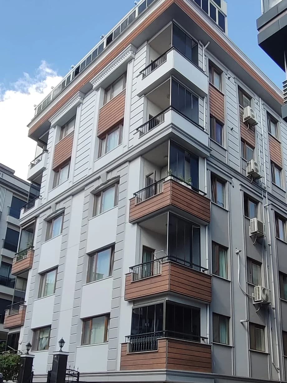 Köşeden aşağıdan bakış: camla kapatılmış balkonlar ve ahşap görünümlü balkon kaplamaları.