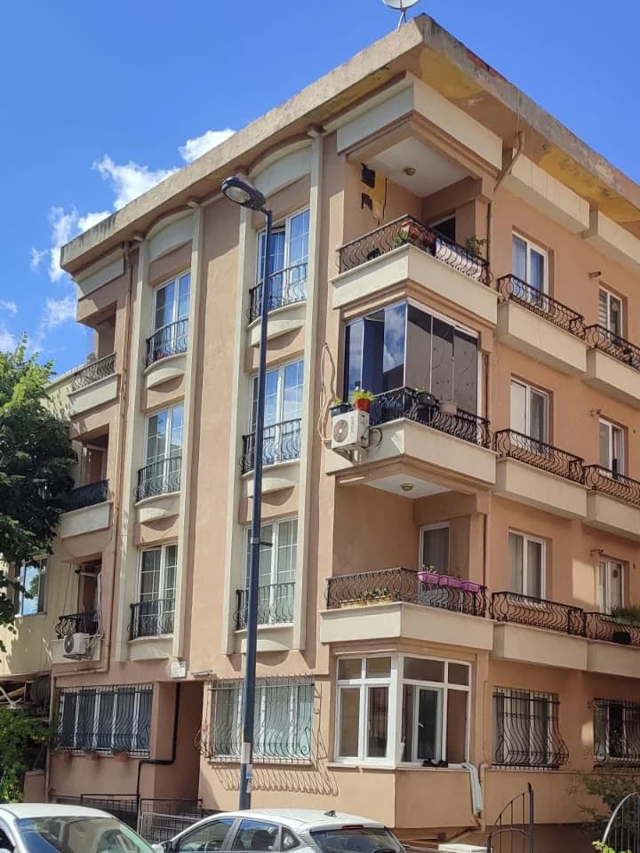 Cephenin orta ve alt katları: ferforje balkonlar ve zemin kattaki beyaz çerçeveli pencereler.
